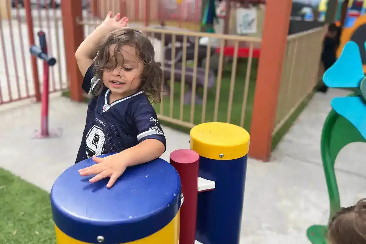 Child learning music in Sierra Preschool's music enrichment program developing rhythm, melody, and musical expression