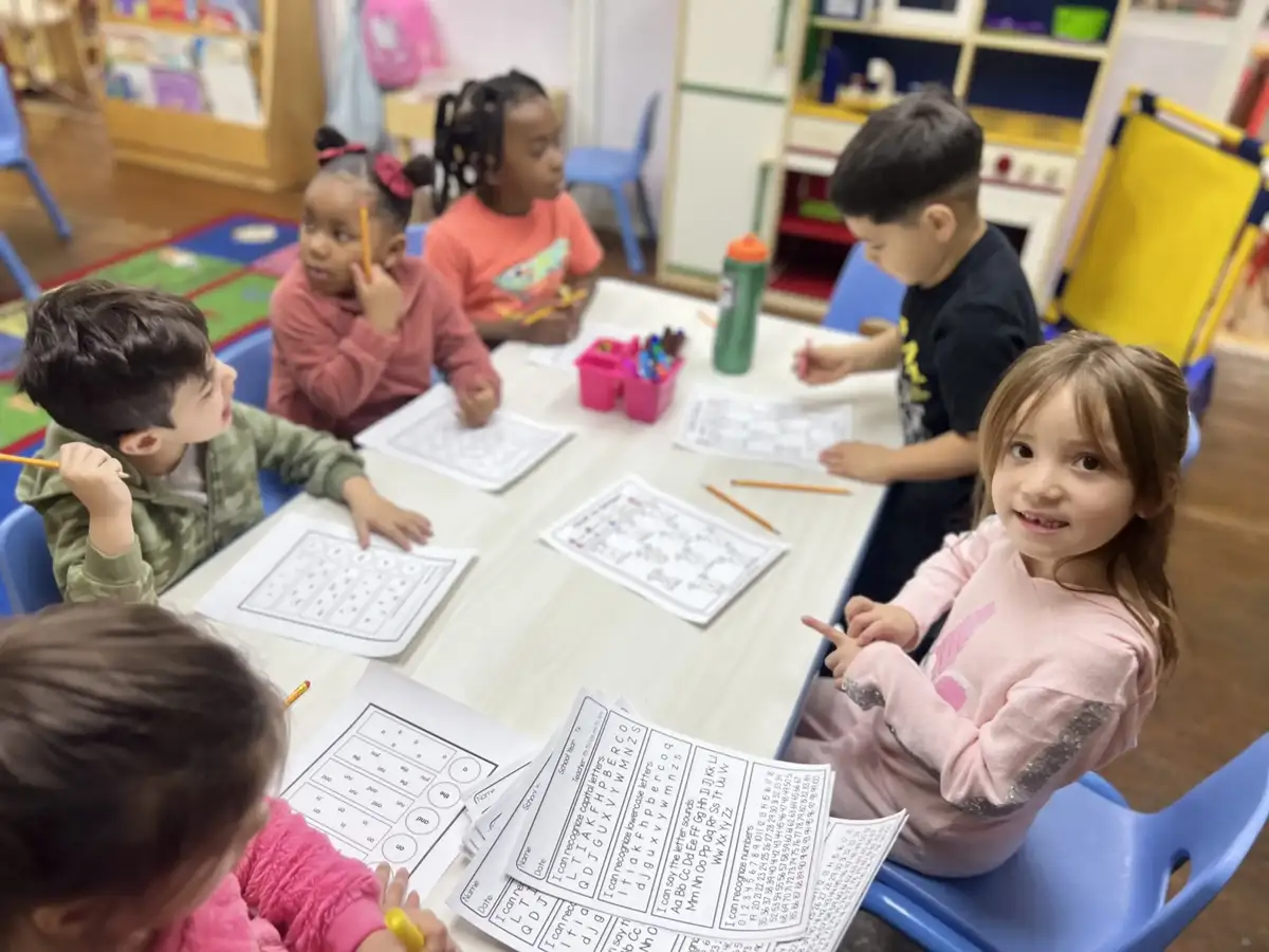 4-year-old Pre-K children at Sierra Preschool working on academic worksheets at a table preparing for kindergarten