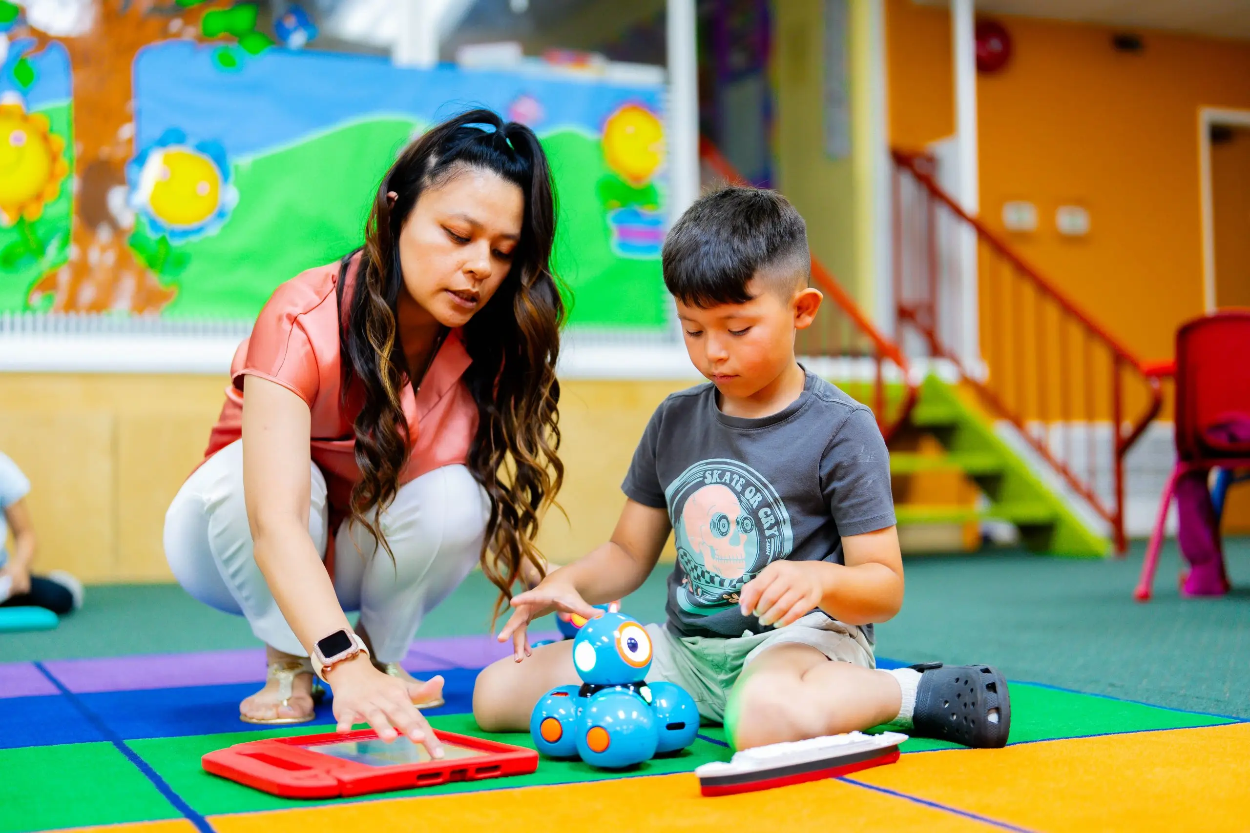 Teacher engaged in one-on-one conversation with a preschool student in Riverside, demonstrating the responsive interaction style that MIT research links to language development