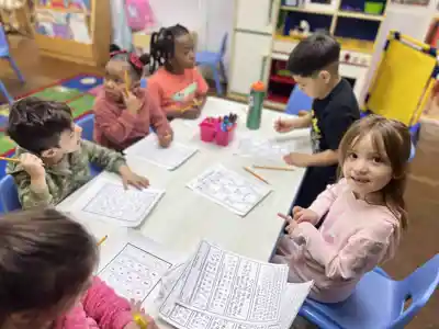 4-year-old Pre-K children at Sierra Preschool working on academic worksheets at a table preparing for kindergarten
